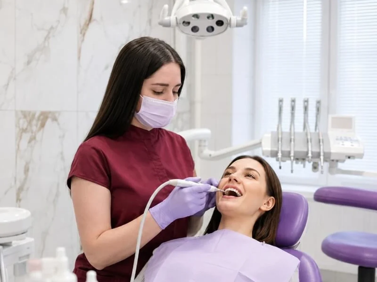 Гигиенист Dentaland осматривает полость рта пациента перед профессиональной гигиеной